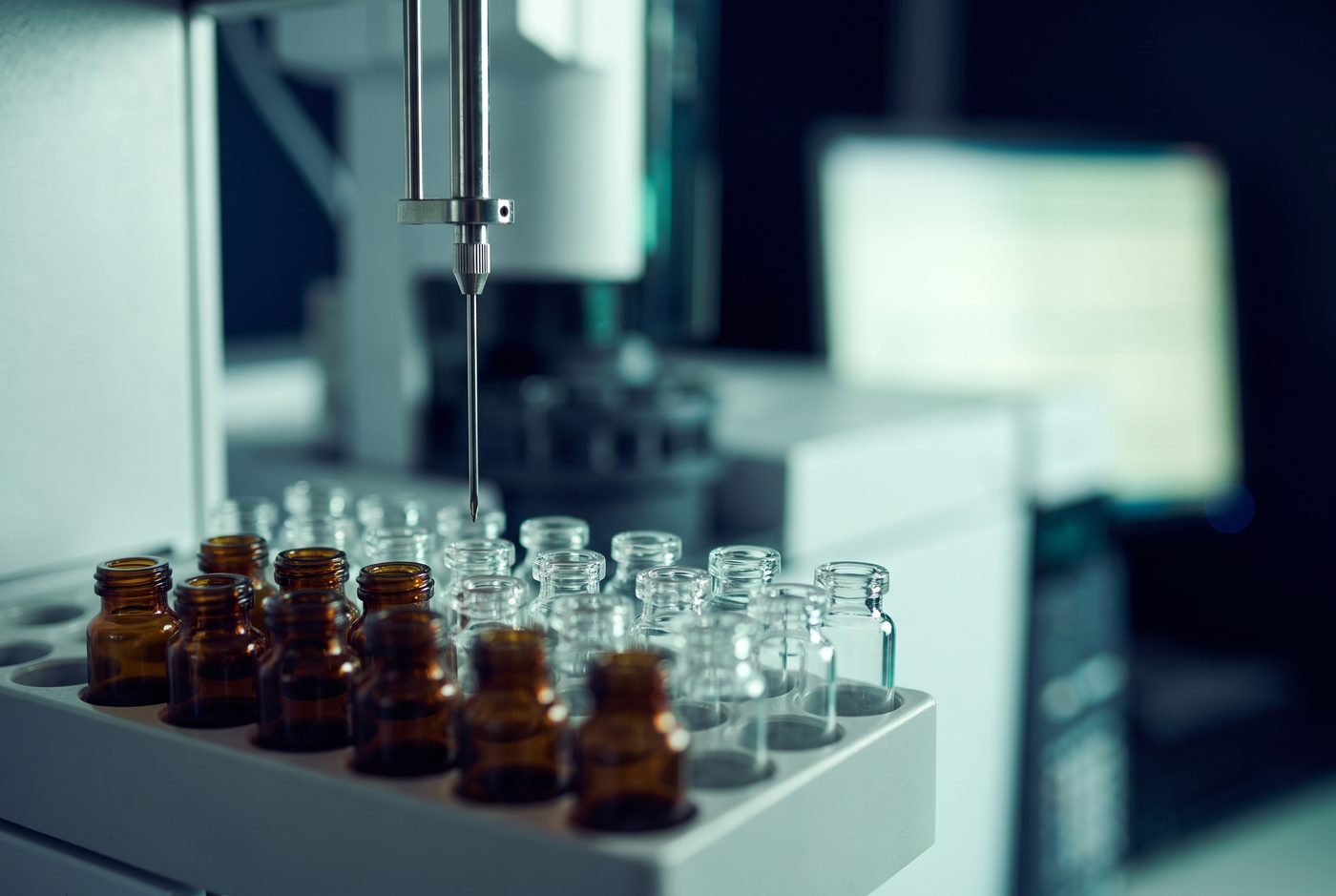 HPLC autosampler needle positioned above rows of sample vials in an analytical testing laboratory