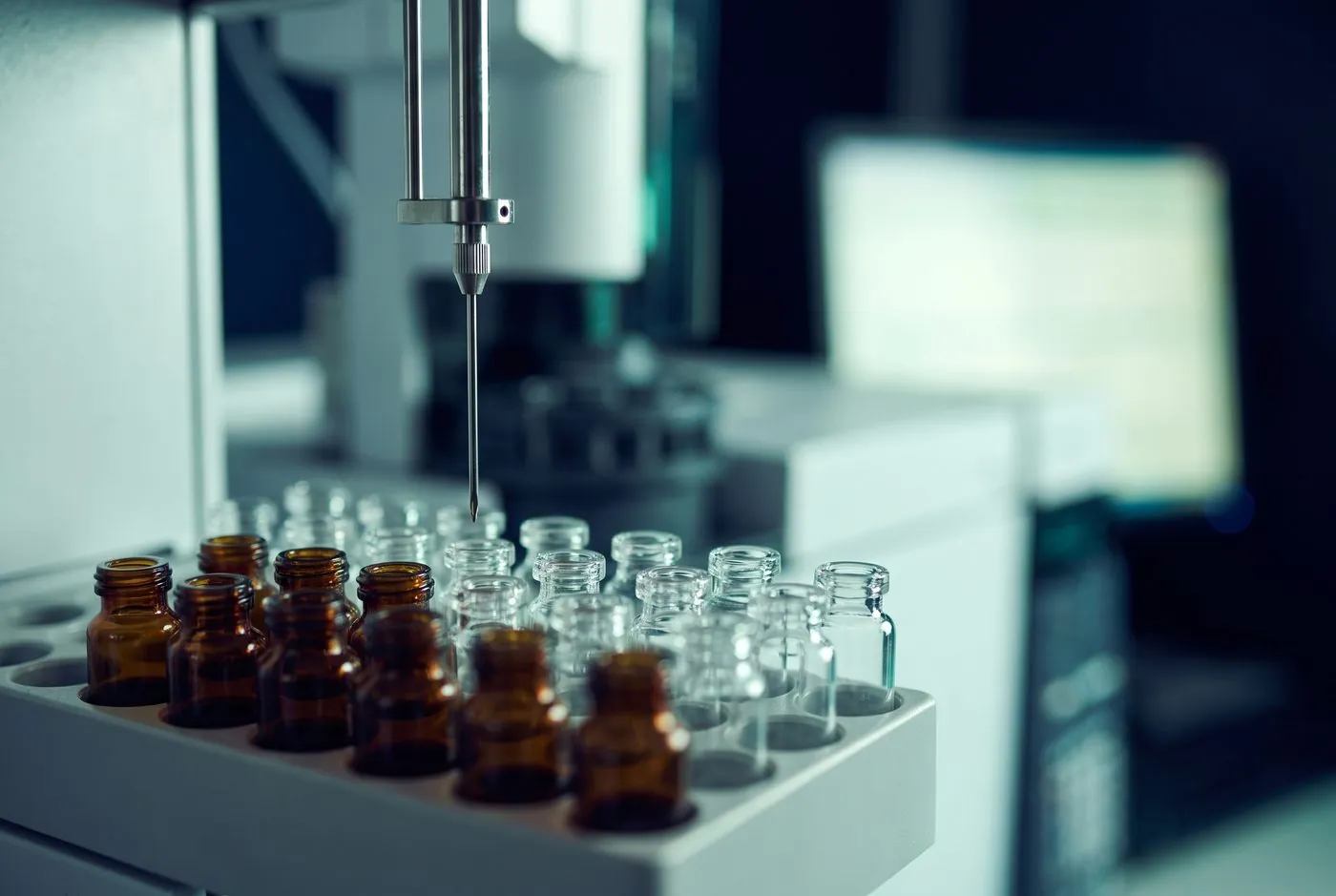 HPLC autosampler needle positioned above rows of sample vials in an analytical testing laboratory